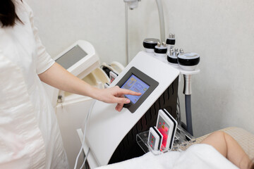 A cosmetologist sets up a modern device with a laser in a beauty salon. Laser pulses cleanse the...