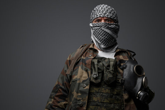 Middle Eastern radical fanatic soldier donning a white keffiyeh and camouflaged field uniform, armed with an automatic rifle, against a gray background - Powered by Adobe