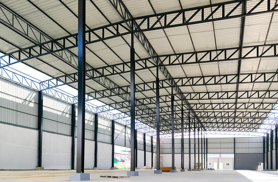 Corrugated steel roof with metal roof beam and columns of new warehouse building structure is under construction in industrial factory area, view from inside and perspective side view