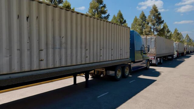 A convoy of 40-foot container trucks waiting on the roadside to get through a border checkpoint.