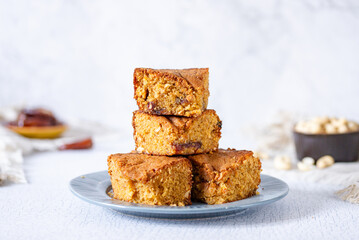 a pile of stacked slices of brown sugar cashew blondies, a vegetarian and vegan dessert with dates, dried fruits on a white background table and plate