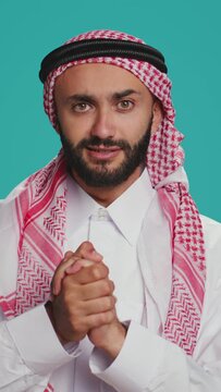 Vertical video Emotional person asking with hope, showing belief and begging for stuff in studio. Arab guy in costume holding prayer hands and having faith. Middle eastern man acting desperate and