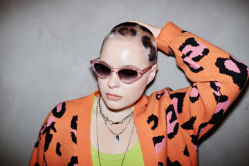 Portrait of confident young woman with cheetah print hair art wearing sunglasses in studio - obrazy, fototapety, plakaty