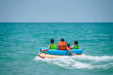 Colorful inflatable boat with father and three children in safety life jackets heading up to open...