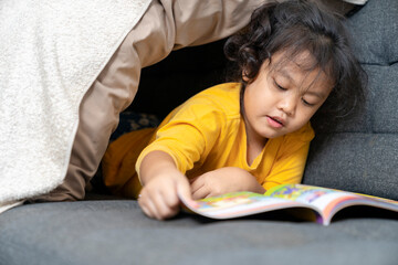 toddler girl with book on sofa at home