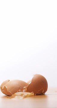 4K footage vertical video Front view SLO MO CU, Chicken eggs fall to the ground shattering on a white background.