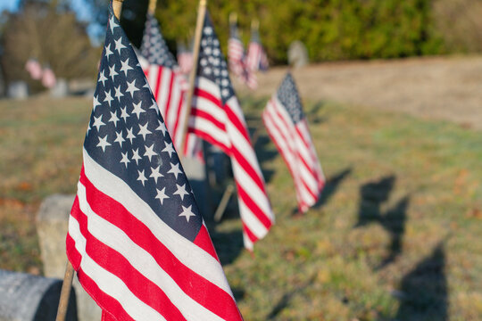American flag background, natural light copy space image, small flags over cemetery thumb stones.
