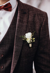 Boutonniere with a rose on the background of the groom's jacket.