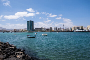 View of the city of Arrecife from the Fermina islet. Turquoise blue water. Sky with big white clouds. Seascape. Lanzarote, Canary Islands, Spain.