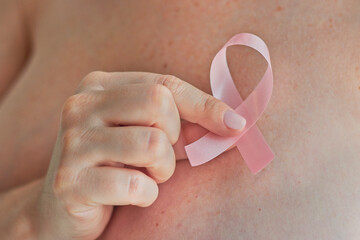 woman hand holding pink ribbon, a breast cancer symbol