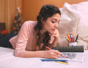Girl drawing and coloring in a coloring book