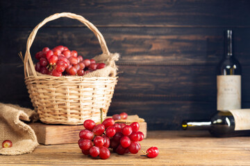 Red grapes with a bunch of grapes in a sweet natural fruit wooden basket with a wine bottle Placed...