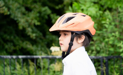 Active kid wearing a bike helmet, Side view  portrait Happy kid with smiling face wearing a cycling helmet riding a bicycle in the park, Concept for safety, Healthy childhood