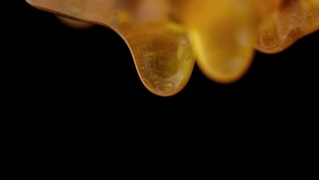 Liquid and fresh honey dripping from wooden honey spoon black background.