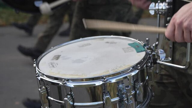 a soldier from a military band skillfully playing the drum. The scene captures the rhythm and precision inherent in military music, reflecting discipline and the ceremonial aspect of military
