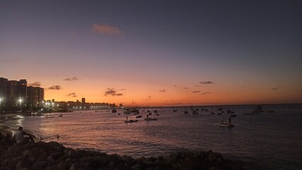 Fototapeta na wymiar Beachfront twilight in Fortaleza; city lights and azure waves under a soft pink sky