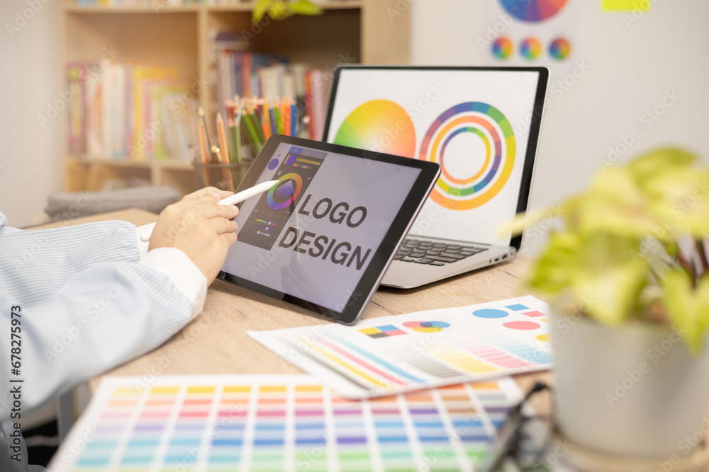 Wall mural designer creating graphic logo on a table using tablet and laptop