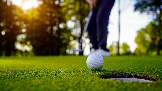 Blurred golfer playing golf in the evening golf course, on sun set evening time.