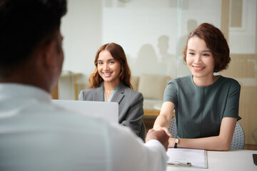 Cheerful hr manager greeting applicant shaking his hand before starting to ask about job experience