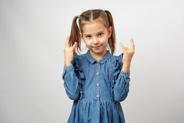 Portrait of a little child girl in denim dress showing rock gesture