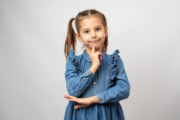 Portrait of a little child girl in denim dress standing with folded hands