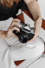 Woman holds vintage film camera sitting chair on white background