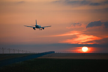 Fototapeta na wymiar Airplane landing on airport runway at beautiful sunset. Themes travel and aviation..