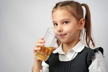 Portrait of happy little girl drinking apple juice from glass