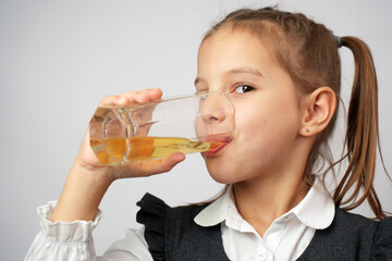 Portrait of happy little girl drinking apple juice from glass