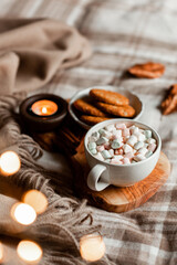 Fototapeta na wymiar warm cozy bedroom interior with cup of hot chocolate on tray, candles christmas lights