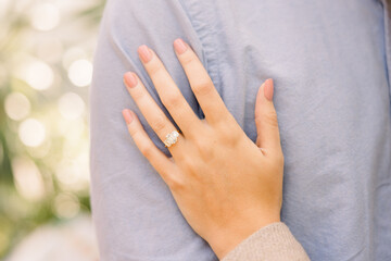 A woman's hand showing off her engagement ring on her fiance's shoulder