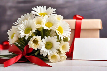 A bouquet of white daisies and a gift box on a table with red satin ribbons, a sheet of notes and red hearts on a light background. Gift for Valentine's Day.