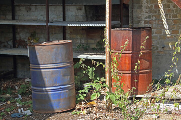 Obraz premium two rusty metal barrels next to an old shelf in an abandoned lot