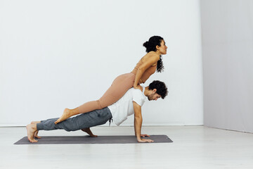 Obraz premium acrobatics woman stretches her back on a man training yoga classes in the gym
