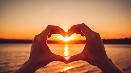 Hands making a heart shape at sunset. Silhouettes of hands showing love