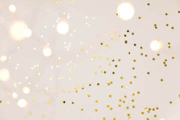 Festive gold background. Shining stars confetti and fairy lights on beige and Set Sail Shampagne background. Christmas. Wedding. Birthday. Flat lay, top view, copy space