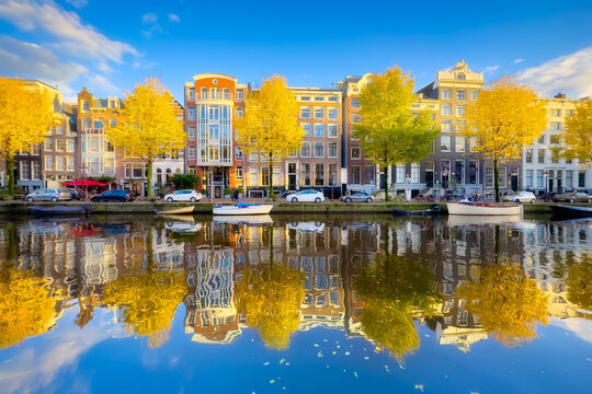 Amsterdam in the fall time.  Capital of the Netherlands. View of old houses and the canal. Reflection on the surface of the water. Yellow leaves on the trees. Postcard, background or wallpaper.