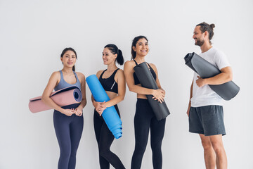 Fototapeta na wymiar Group of male and female friends with yoga instructor standing holding yoga mats and talking after break, exercising, doing yoga, class in studio.Healthy lifestyle and wellness concept