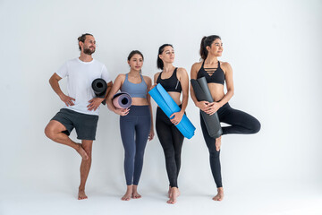 Fototapeta na wymiar Group of male and female friends with yoga instructor standing holding yoga mats and talking after break, exercising, doing yoga, class in studio.Healthy lifestyle and wellness concept