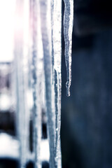 Icicles hang from the roof of the house in sunny weather