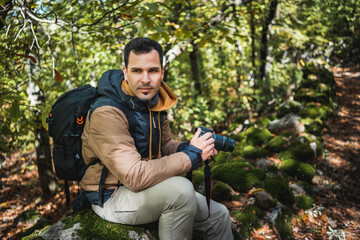 profile portrait of young and beautiful photographer resting on a stone in the forest after walking and photographing the wonders of the environment © Marko Domka