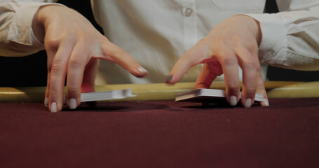 Croupier playing poker in casino. Close-up of hands and chips on table

