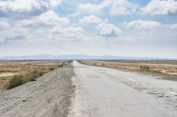 Fototapeta na wymiar Asphalted highway in the middle of the desert in Uzbekistan, bad road in the desert