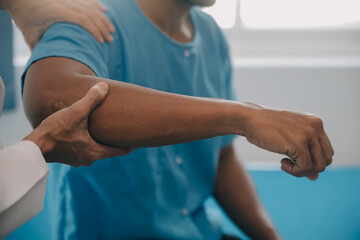 Doctor or Physiotherapist working examining treating injured arm of athlete male patient, stretching and exercise, Doing the Rehabilitation therapy pain in clinic.