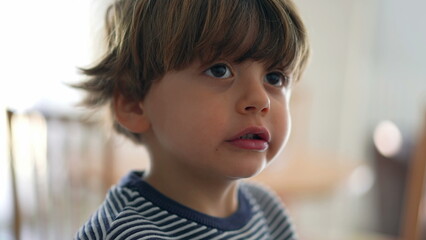 Child chewing food with open wide mouth, close-up face of little boy eating chewy food, mastication cocnept in deep concentration