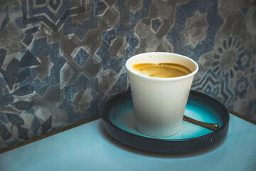 latte art with milk foam and milk and espresso in a white paper cup