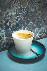 latte art with milk foam and milk and espresso in a white paper cup