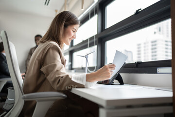 Asia businesswoman working of paperwork and tablet computer with team business background