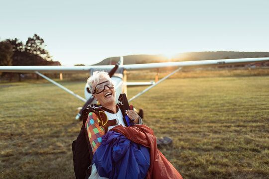 Smiling senior woman after successful skydive on grass field