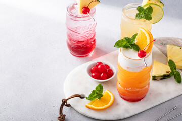 Variety of tropical tiki cocktails with cold foam, garnished with orange slices, cherry and mint